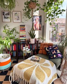 a living room filled with lots of plants next to a window and bookshelf