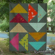 a quilted wall hanging on the side of a tree in front of a road