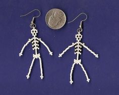 the skeleton earrings are made out of tiny white beads and silver hooks, with a penny in the background