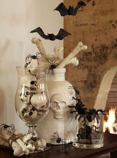 halloween decorations in glass vases with bats and skulls on the table next to them