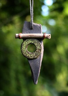 a piece of metal hanging from a rope with a green object on it's end