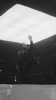 a black and white photo of a man in a suit waving to the crowd at a sporting event