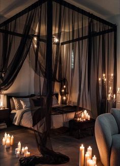 a canopy bed with candles on the floor in front of it and a couch next to it