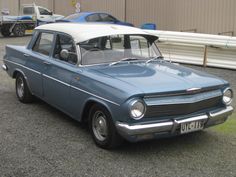 an old blue car parked in a parking lot