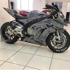 a silver motorcycle parked in a showroom next to other motorcycles on the tile floor