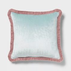 a light blue and pink pillow with fringe trim on the bottom, in front of a white background