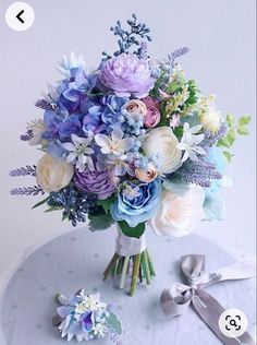 a bouquet of flowers sitting on top of a white table next to a silver ribbon