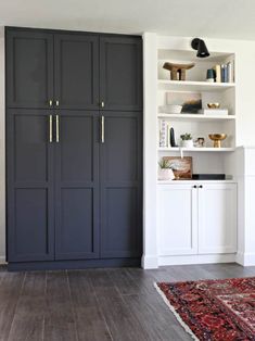 a living room with white shelves and dark blue painted cupboards on the wall, along with a red rug