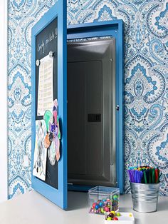 an open blue box on top of a white desk next to a bucket of colored pencils