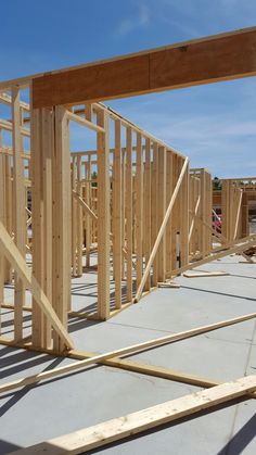 a house being built with wooden framing in the foreground and blue sky in the background