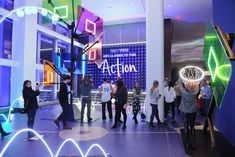 a group of people standing in front of a building with neon signs on it's walls