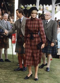 a woman in a plaid dress and hat walks with other people at an outdoor event