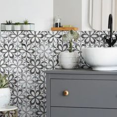 a white sink sitting on top of a gray dresser next to a potted plant