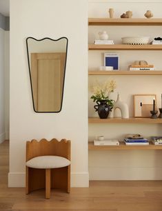 a room with some shelves and a mirror on the wall next to a chair in front of it