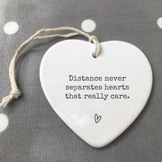 a ceramic heart hanging on a string with the words distance never separates hearts that really care