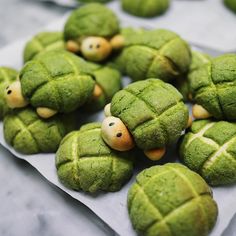 there are some green cookies shaped like animals on top of each other, with faces drawn on them