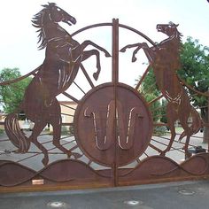 a large metal gate with two horses on it's sides and the letter u