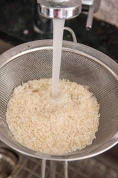 rice is being washed in a strainer