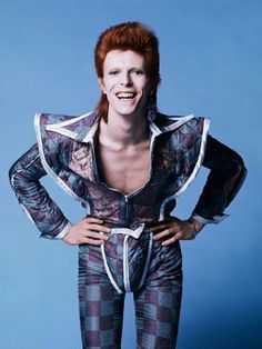 a man with red hair is posing for a photo wearing a suit that has checkered pattern on it