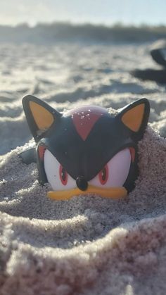 a close up of a toy in the sand with an animal face on it's head