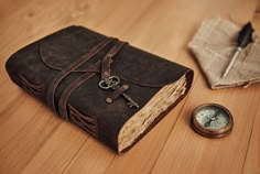 an old book with a pocket watch on the floor next to it and a compass