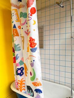 the shower curtain is hanging in front of the bathtub with colorful designs on it