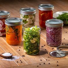 several jars filled with different types of food and seasonings on top of a wooden table