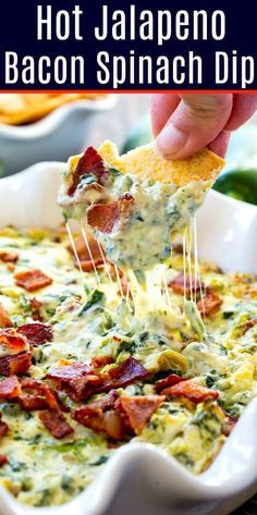 a hand holding a tortilla chip with bacon and spinach dip