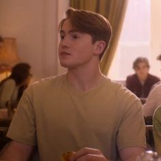 two people sitting at a table with food in front of them and one person standing up