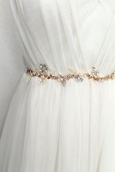 a white dress with gold and crystal beads on the waist, along with a belt