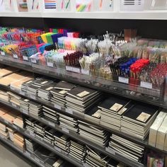 there are many pens and pencils on the shelves in this store that is filled with books