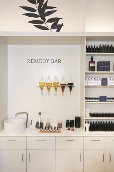 a white counter with bottles and soaps on it in a room filled with shelves