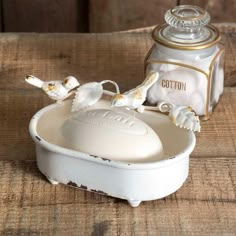 an old fashioned white bowl with two birds on it and a canister in the background