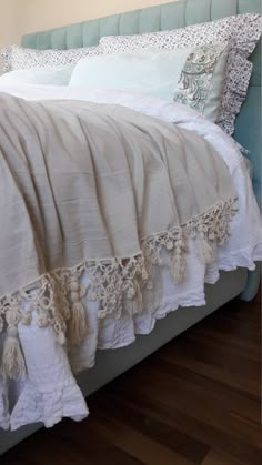 a bed with white linens and tasselled pillows