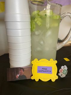 there is a pitcher of water next to a card with the name pickle margarita on it