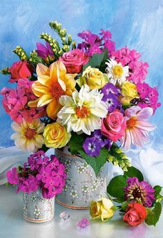 a vase filled with lots of colorful flowers on top of a white cloth covered table