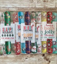 christmas wrapping paper rolls are lined up on a wooden surface with holiday greetings in them