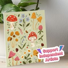 a card with an image of mushrooms and flowers on it, next to a potted plant