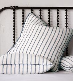 two striped pillows sitting on top of a bed next to a black iron headboard