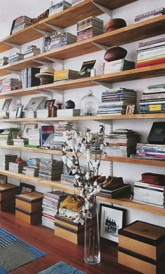 a book shelf filled with lots of books next to a vase full of white flowers