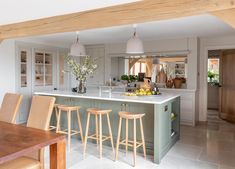 a kitchen with an island and bar stools next to it, in front of a dining room table