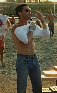 a man with bandages on his arm standing in front of a group of people at a beach