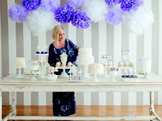 a woman standing in front of a table filled with cakes and cupcakes on it