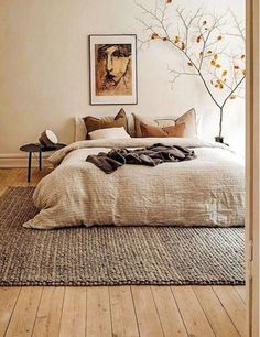 a large bed in a bedroom next to a painting on the wall and wooden floors