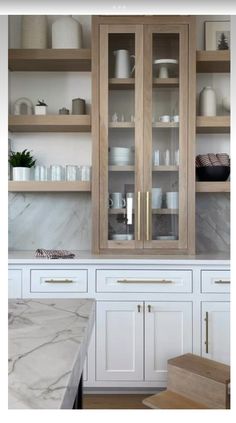 a kitchen with marble counter tops and wooden cabinets in the center, along with white cupboards