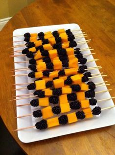 several skewers of cheese and blackberries are arranged on a white platter