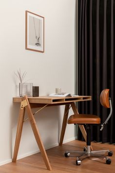 a wooden desk with a chair next to it and a framed photograph on the wall