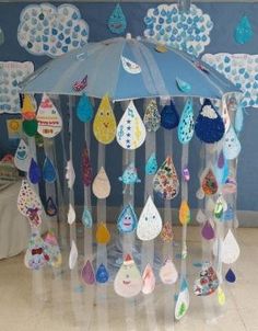 a blue umbrella is hanging from the ceiling in front of a wall with clouds and raindrops