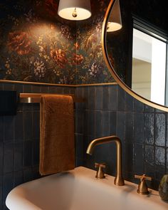 a bathroom sink sitting under a mirror next to a wall mounted faucet with a towel hanging on it