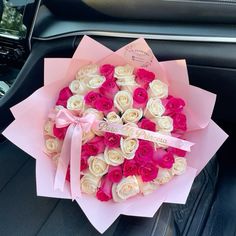 a bouquet of roses is sitting in the back seat of a car with a pink ribbon